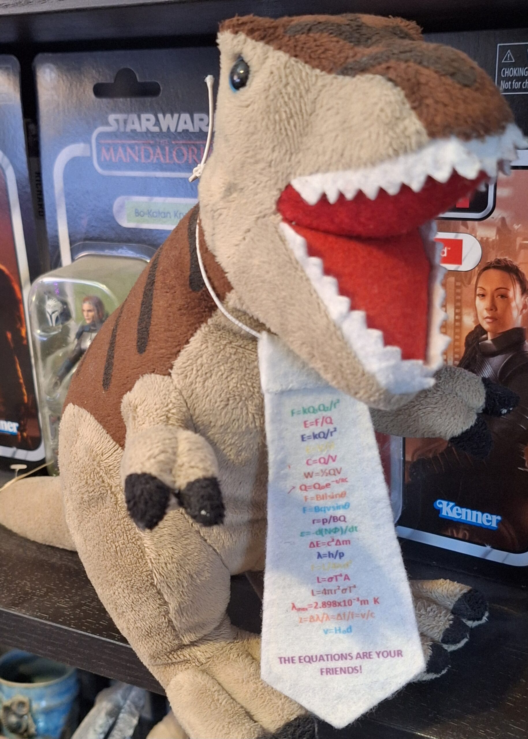 A stuffed T-Rex wearing a customised tie listing physics equations